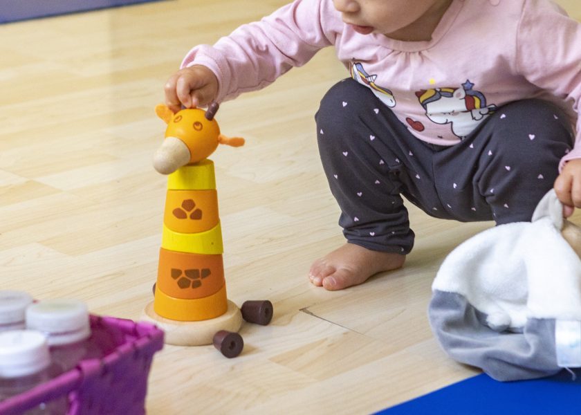 [foto di una bimba in un momento di apprendimento, infatti sta giocando con delle forme in una sala]